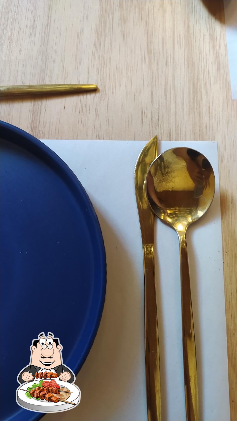Detalle de cubiertos dorados y palillos sobre mesa Kimono